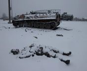 A dead soldier (covered by fresh snowfall) from the Russian Army, alongside a disabled and damaged MT-LB (APC) armoured personnel carrier, near a road leading to the city of Kharkov, Ukraine. The Russian invasion of Ukraine, February 25th, 2022. from apc
