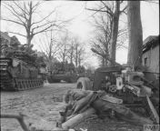 Churchill tanks laden with infantry of the 9th Durham Light Infantry pass a knocked out German PAK 40 7.5cm anti-tank gun and one of its unfortunate crewman as they enter Schilberg, Netherlands. 20 January 1945. from sil pak xn