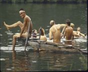 Nude young man sitting on dock grinning while he displays leg as he and friends enjoy skinny dipping in river during Woodstock Music &amp; Art Festival (Bethel, New York 1969) [2100x1385] from incest nude young